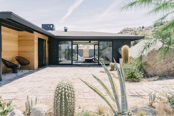 The couple added a coat of black paint and cedar siding to give the home a cleaner, more modern look. "The house already had wide and low eaves, providing protection from the sun, and we added new spray-foam insulation, so the black exterior actually does not pose too much of an issue with the desert heat," she says. A new Cor-Ten steel fence blocks the view of the neighbor's roof, but doesn't interfere with the landscape. 