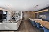 Modern home with Living Room, Shelves, Table, Medium Hardwood Floor, and Lamps. The space is divided up to provide maximum openness inside and in terms of its connections with the outside to create a feeling of space larger than the apartment’s actual dimensions. Photo of The Layers apartment