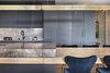 Modern home with Kitchen, Pendant Lighting, Marble Counter, Wood Cabinet, Light Hardwood Floor, Colorful Cabinet, Wood Counter, and Marble Backsplashe. The kitchen island and the dining table positioned in the center of the space were united into a single unit by bringing together one natural material with another in layers – the tabletop is solid wood, which both penetrates into and surrounds the island. In essence, this creates the look of an island comprising three layers of different materials placed one on top of the other. Photo 4 of The Layers apartment