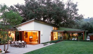 The large pocket doors of Mandeville Canyon House open up the corner of the living room to the concrete terrace and lawn beyond. This house, designed by Dutton Architects, is perfect for informal living and taking advantage of the southern California climate.