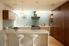 Modern home with Kitchen, Refrigerator, Cooktops, Wood Cabinet, Range Hood, Wall Oven, Ceiling Lighting, Range, Drop In Sink, Ceramic Tile Backsplashe, Medium Hardwood Floor, and White Cabinet. The new kitchen is modern and utilitarian, modest yet open and spacious. The U-shaped counters face the views on one side, and bookended by a skylit wall of hand-cut blue ceramic tile. The long skylight over the back counter helps balance the light from the windows opposite, and gives a warm wash of light over the work space all day long. Photo 3 of Los Feliz Residence