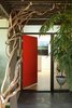 Modern home with Hallway, Exterior, Doors, and Swing Door Type. A view of the entry from outside. One enters the house from under a pergola of wisteria, and is immediately within a house of light. A large skylight over the wall at the end of the entry serves as both an art wall, and a way of welcoming you with light in a formerly dark area. Photo 6 of Los Feliz Residence