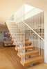 Modern home with Staircase, Metal Railing, and Wood Tread. The staircase appears to cascade down to the lower floor and be suspended from narrow white steel rods. The treads are solid white oak, stained to match the floor, and are thick enough to allow there to be no risers. A 14′ long skylight over the stair allows light to now come down into the lower floor. Photo 8 of Los Feliz Residence