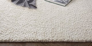 Wool loops of varying thickness form the pebble-like ground of Ria rug.