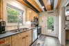 Modern home with Kitchen, Wood Backsplashe, Engineered Quartz Counter, Range Hood, Wood Cabinet, Microwave, Dark Hardwood Floor, Dishwasher, Undermount Sink, Recessed Lighting, and Ceiling Lighting. kitchen cabinets made from left over Advantech sub flooring Photo 8 of Mountain Bikers Tiny House Getaway