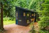 Modern home with Exterior, House Building Type, Metal Roof Material, Metal Siding Material, and Shed RoofLine. The two-level home rests on a lush property surrounded by 80-foot-tall trees. Simple black steel siding lends texture to the home’s facade. Photo 2 of Guemes Island Home