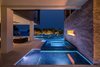 Modern home with Outdoor, Trees, Hardscapes, Small Pools, Tubs, Shower, Back Yard, Landscape Lighting, and Small Patio, Porch, Deck. The pool flows from a secluded enclave featuring a vanishing edge 8-person spa adjacent to an attractive fire feature embedded within an engineered support wall cladded by MSI. Guests can capture the simplicity of water and fire with views of the mangrove trees lighting the night across the pool. Glass tile by Mosaicist. Original outdoor living design by Ryan Hughes Design Build. Photo 5 of Nirvana Home