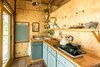 Modern home with Kitchen, Pendant Lighting, Drop In Sink, Colorful Cabinet, Medium Hardwood Floor, Stone Tile Backsplashe, Cooktops, Wood Counter, and Refrigerator. The kitchen has a small fridge, 2 burner stove top, and filtered rain water. Photo 3 of Off Grid Cabin in the Texas Hill Country