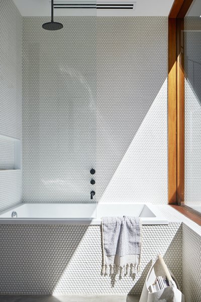 White penny tiles reflect natural light in the bathroom.