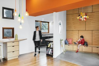 The angled entry foyer is wrapped in plywood with concealed access to roof storage spaces. Built-in seating provides storage for daily wares and a spot to put on shoes and drop school bags.