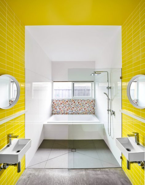 The majority of the boys’ bathroom is clad in economic, white ceramic tile. A band of yellow tiles delineates each boy’s personal area, and the color continues across the ceiling. The Andy Warhol pixelated tiles by Dune were an indulgence, and they were used sparingly for impact.