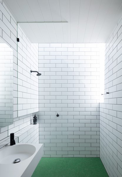 Green floor tiles add a surprising pop of color to this bathroom.