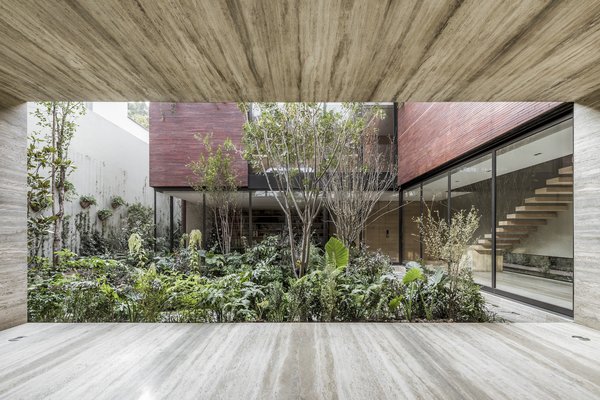 The monolithic brick home in Mexico City by Esrawe Studio looks imposing from the street, but its enormous pivoting door opens to a courtyard that feels like a lush oasis.