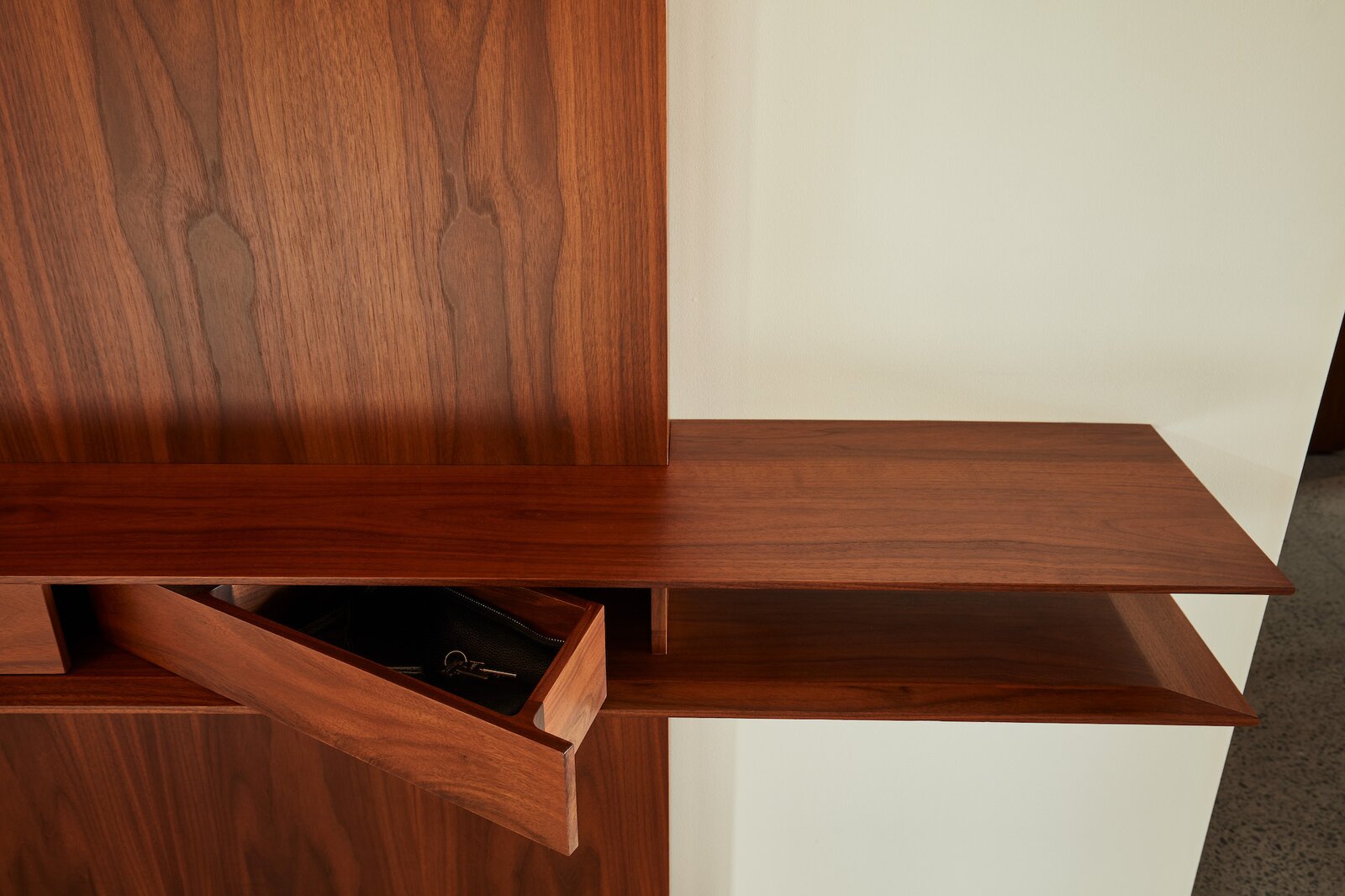 At the entry, a hidden walnut cabinet provides a place to keep wallets, keys, phones, and other distractions, signaling that the home is a place of relaxation.