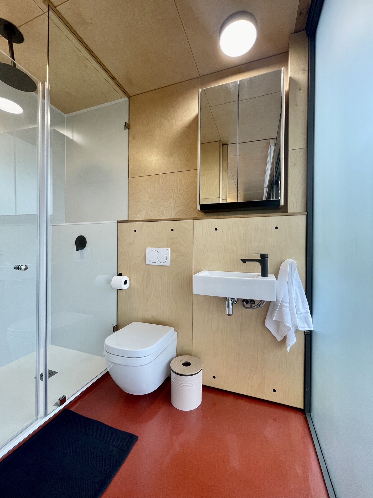 The simple bathroom features a the same palette as the rest of the interior. Opaque glass allows natural light into the space whilst maintaining privacy.