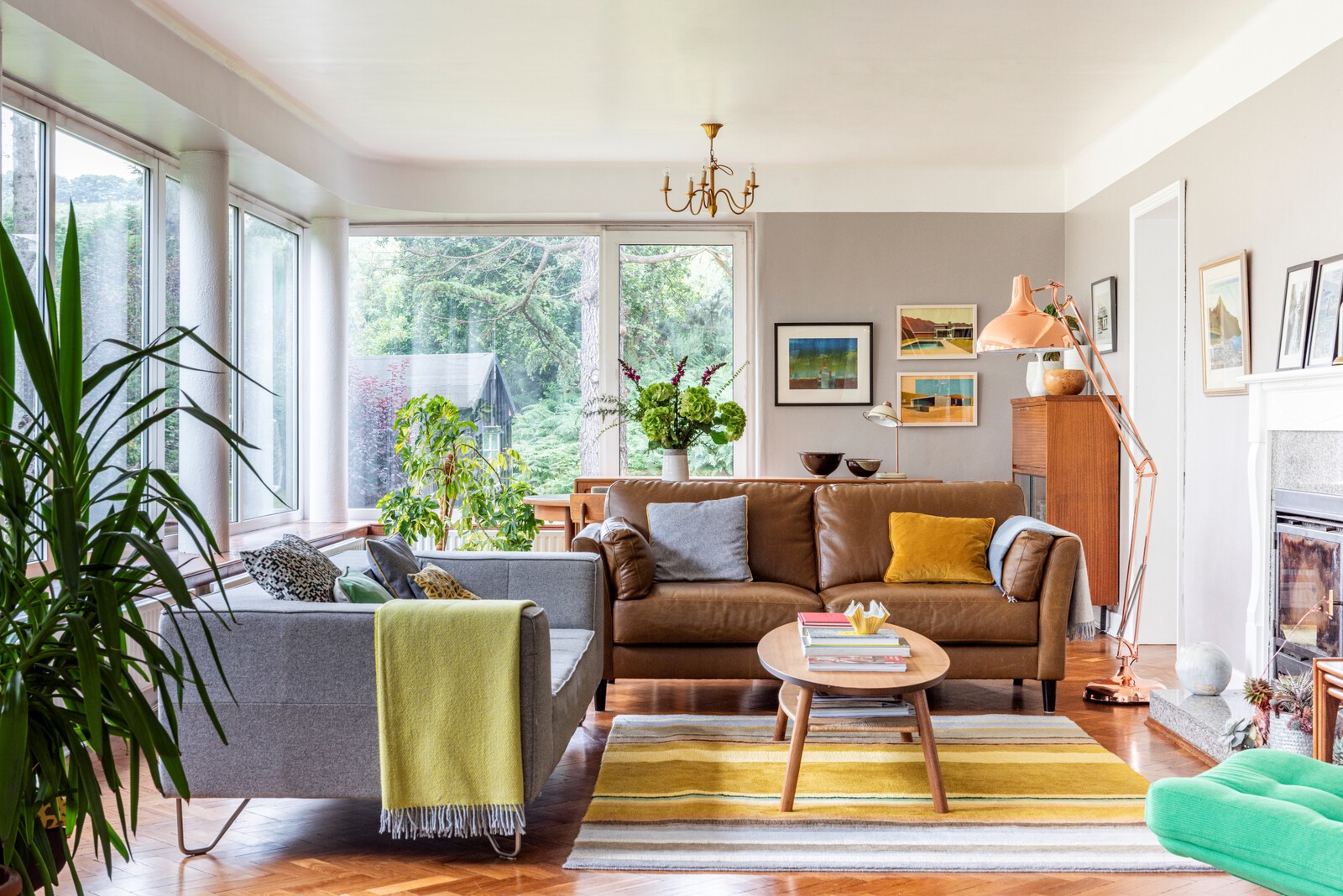 The living area is a bright space surrounded by windows on two sides. While the interior itself is fairly neutral, the furnishings and artwork introduce bright pops of color.