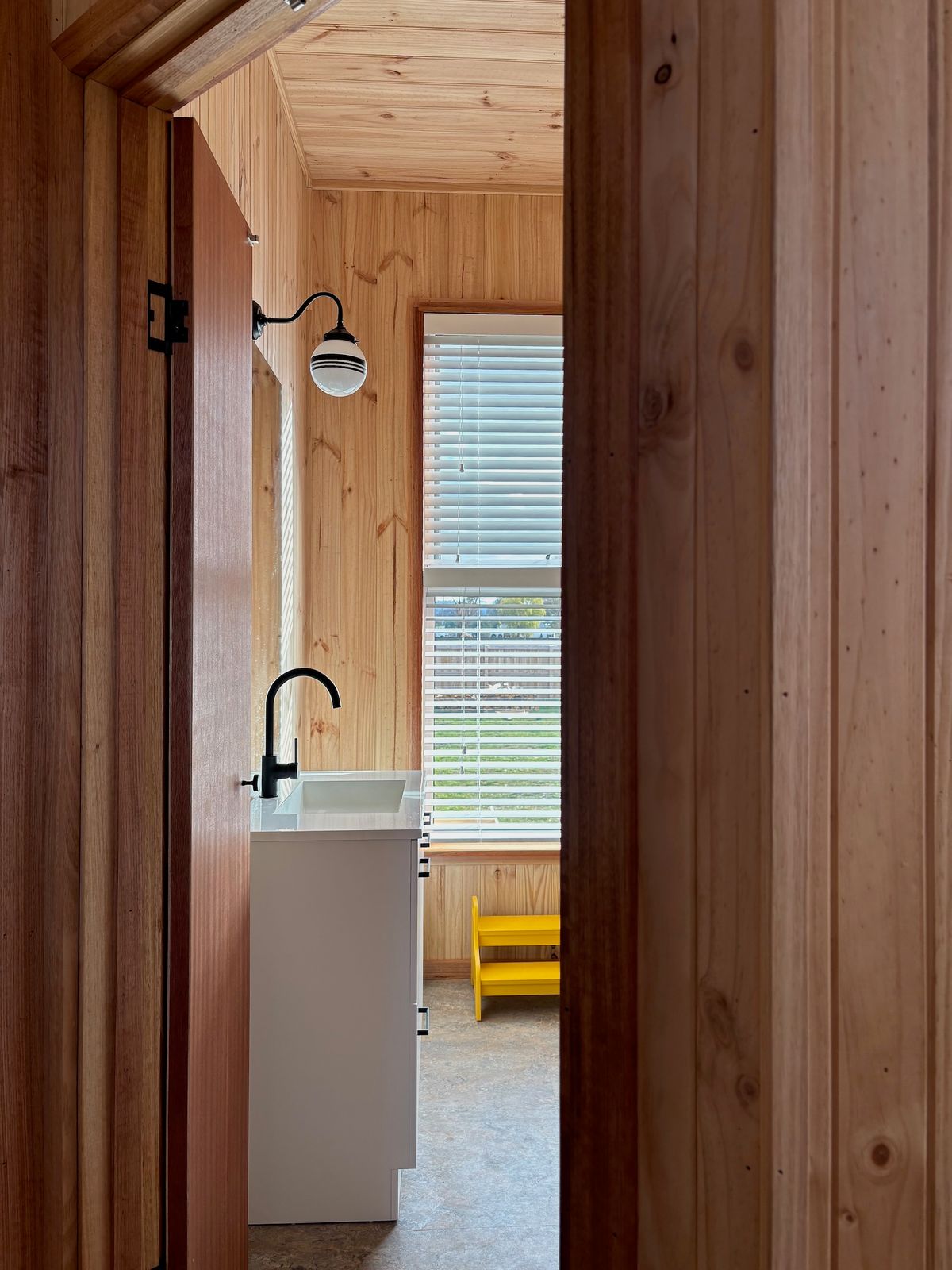 Like the rest of the home, the bathroom is clad in timber and features linoleum flooring, a natural material made using linseed oil. This approach negates the need for costly tiles. 