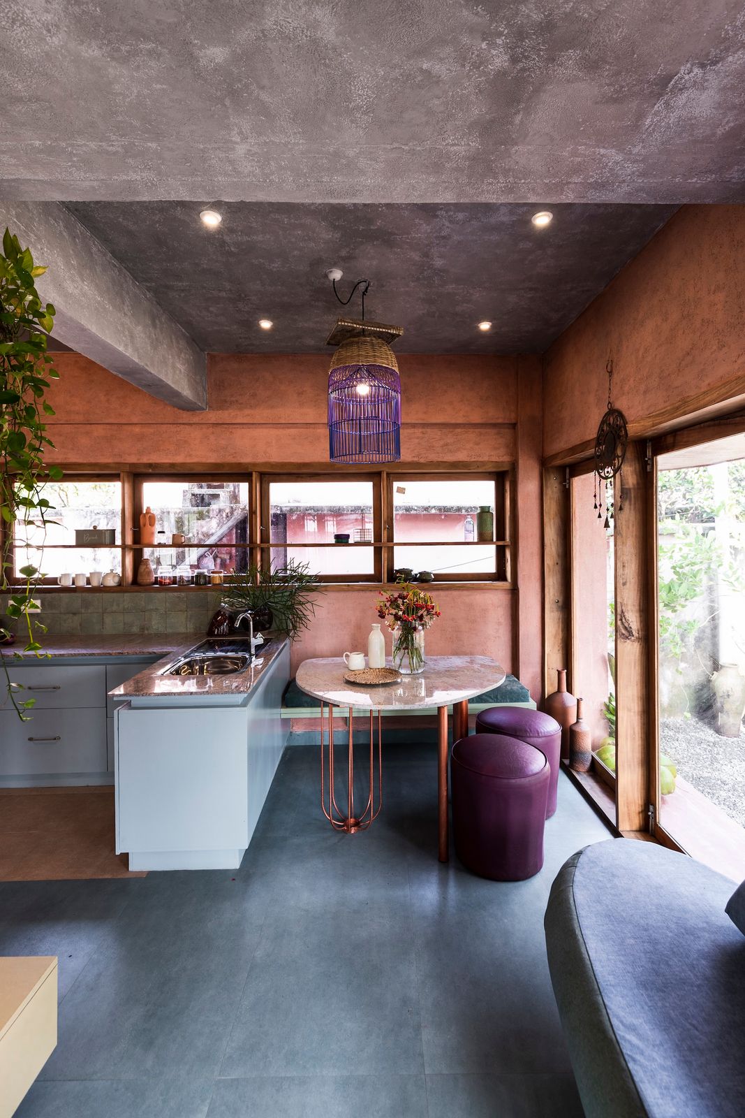 The dining table was custom-made from scrap, with salvaged stone slabs for the surface and bent TMT bars forming the legs. NO Architects drew up the design and it was crafted by a local artisan. The sofa and built-in bench were also crafted from leftover materials, resulting in the playfully mismatched upholstery.