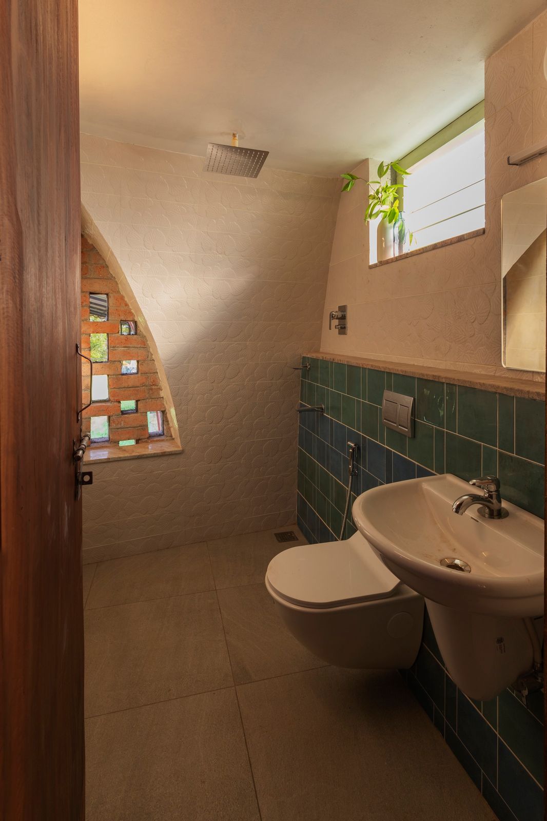 The bathroom on the upper floor features an open shower and is ventilated naturally via the perforations in the jaali. The tiles were donated by a local sponsor.