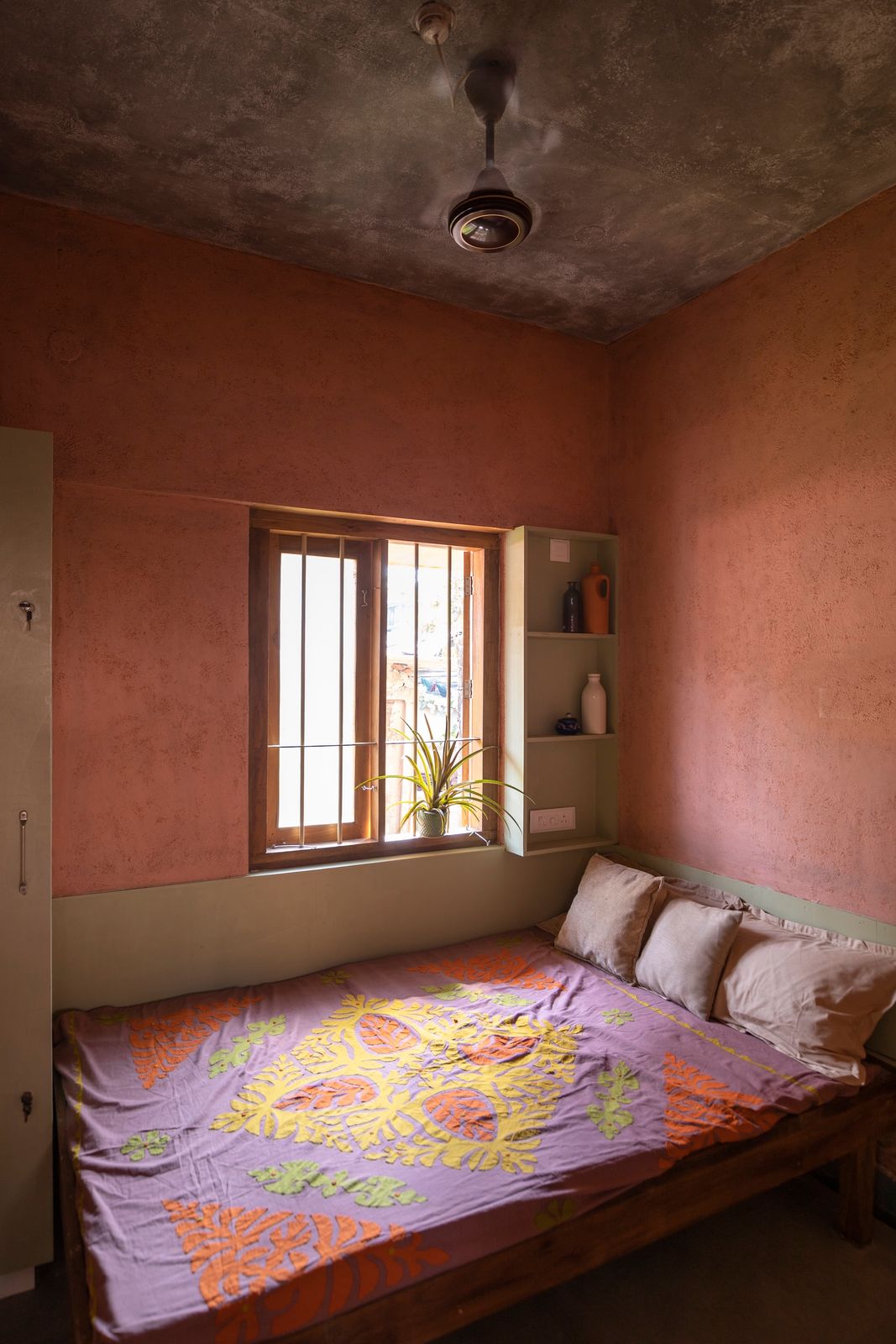 The bedroom on the ground floor features in-built shelving and a bed frame built using scrap timber.