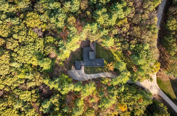 The L-shaped plan and detached garage sit within a clearing on the family's two-acre wooded lot on Raynes Neck, a peninsula located about half a mile from the ocean. The cedar exterior of the home, Gendai Linseed Black yakisugi by Nakamoto Forestry, all but disappears into the surrounding forest.