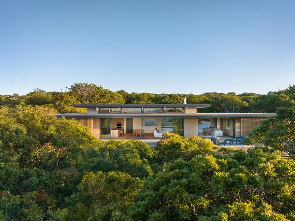 The home sits among the trees on the western edge of Martha’s Vineyard. Floor-to-ceiling glass doors on both sides of the home can be opened up to allow the ocean breezes to pass through the interior. 
