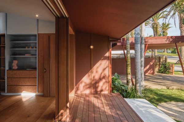Timber sliding doors allow the house to open almost completely to the deck—connecting the kitchen to the front garden and street—while the deep overhang provides shade from the subtropical sun