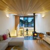 Modern home with Living Room, Medium Hardwood Floor, Chair, Wall Lighting, Sectional, and Wood Burning Fireplace. The third floor living room - an urbanized version of a cabin in the woods, with wood stove and cedar ceiling. It nestles intimately into tree tops at one end, and opens widely toward the sky at the other. Photo of Bellwoods Lodge