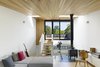 Modern home with Living Room, Chair, Wood Burning Fireplace, Sectional, and Medium Hardwood Floor. The third floor living room - an urbanized version of a cabin in the woods, with wood stove and cedar ceiling. It nestles intimately into tree tops at one end, and opens widely toward the sky at the other. Photo 6 of Bellwoods Lodge
