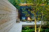 Modern home with Outdoor, Wood Fences, Wall, Wood Patio, Porch, Deck, and Large Patio, Porch, Deck. The kitchen & dining areas open out to a secluded and densely treed back yard with picnic table, lounge seating, and fire pit, evoking an intimate campsite in the heart of the city. A garden storage pavilion with oversized sliding doors provides access to a private lane beyond, while doubling as a podium for canoe storage. Photo 14 of Bellwoods Lodge