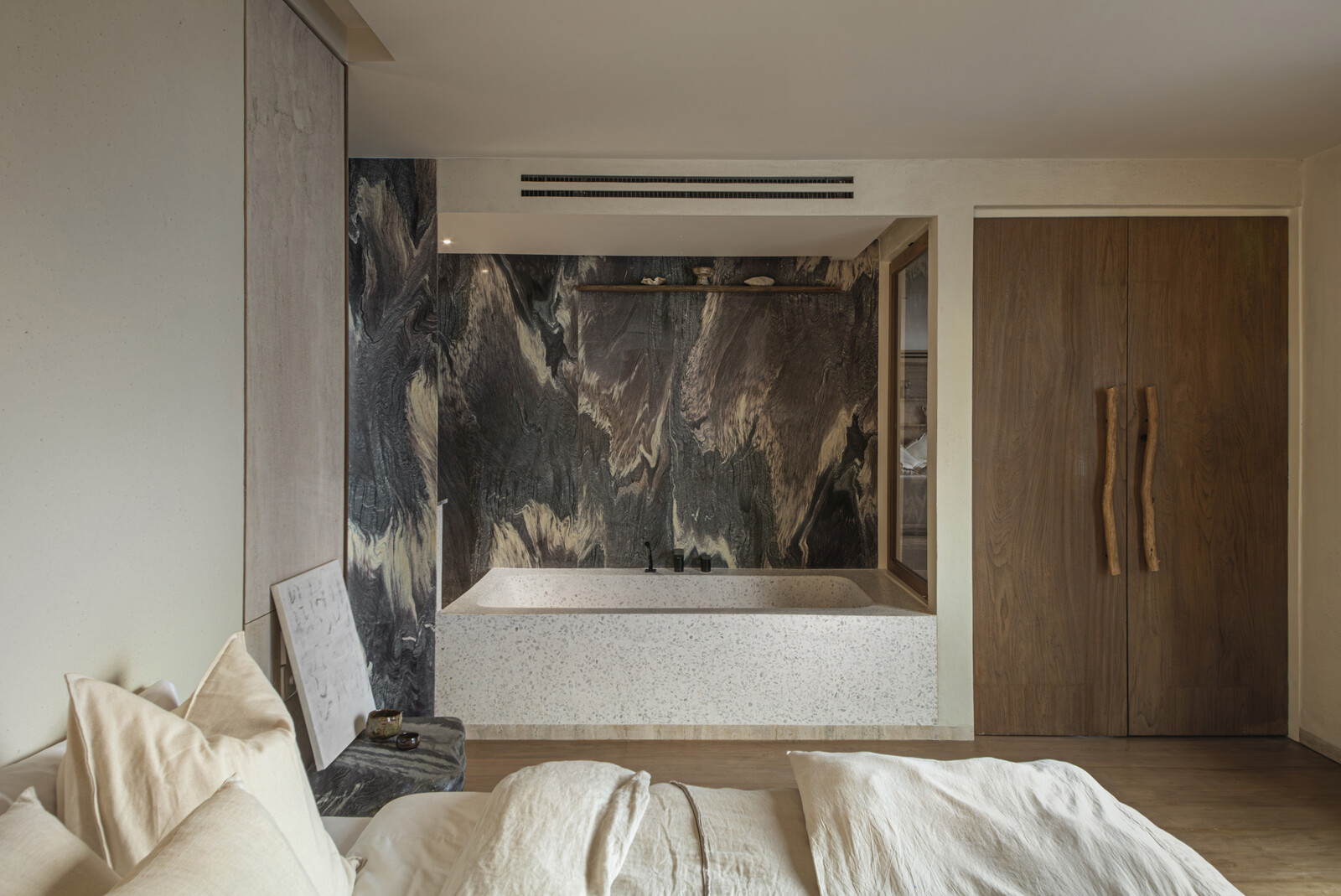 The master bathroom's tub backed by Rosso Luana stone is an artistic space. 