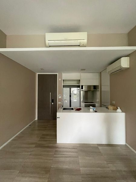 The open kitchen located next to the entrance door was fitted with functional white cabinetry. The beige marble flooring had no character and did not match taupe painted walls.