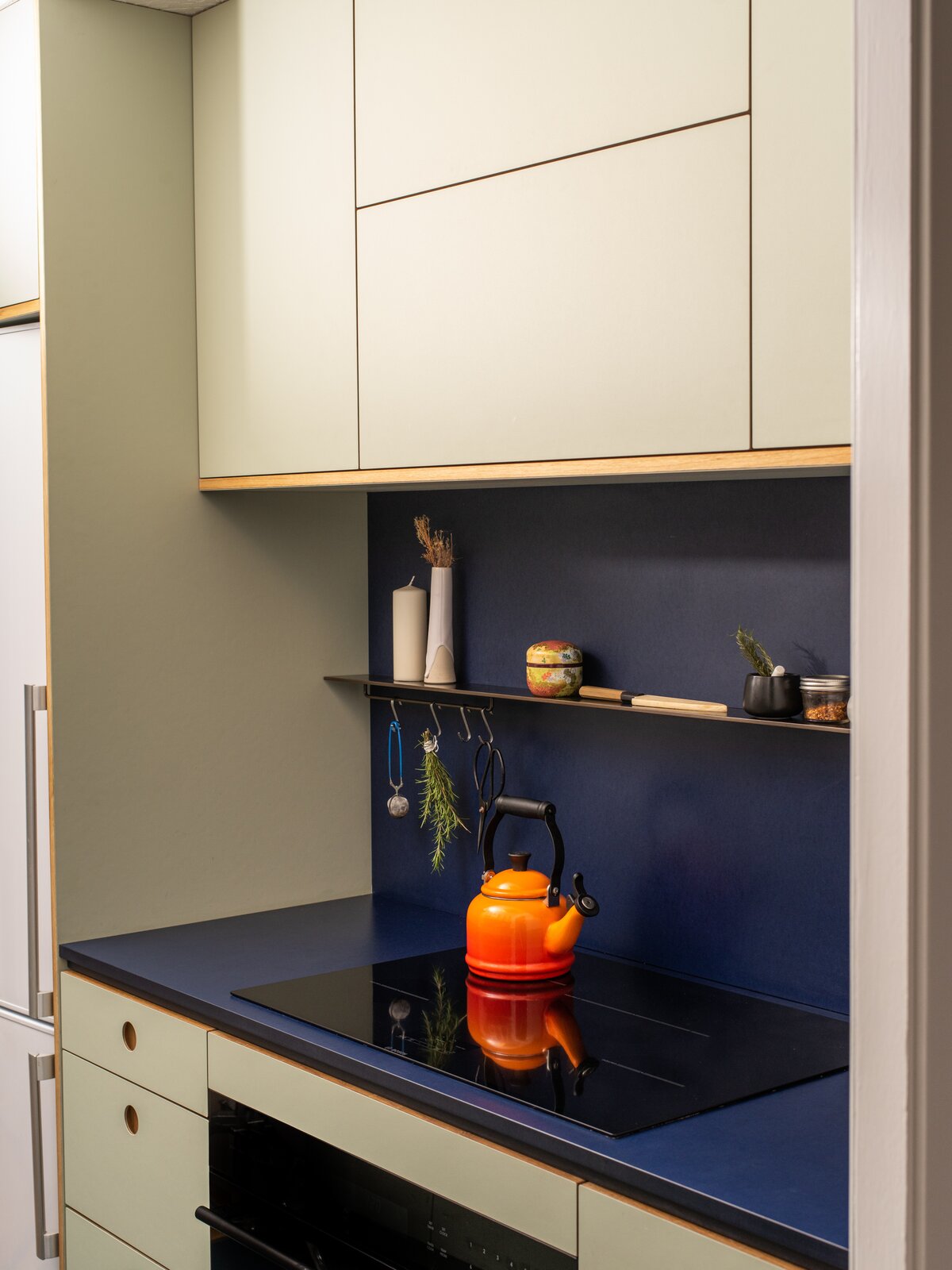 Raising the cabinet height and installing new color-blocked Richlite counters and full-height backsplash help the kitchen feel larger.