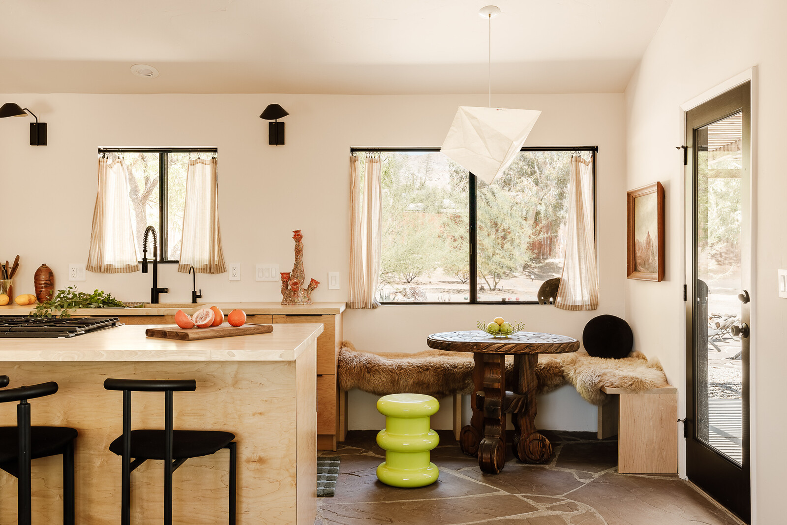 A new breakfast nook off the kitchen creates space for casual dining. Replacing a sliding door with a single opening created more space for seating, while still offering ease of access to the patio. The neon green stool is Kartell Pilastro from Design Within Reach, and the table is vintage from Laguna Vintage.