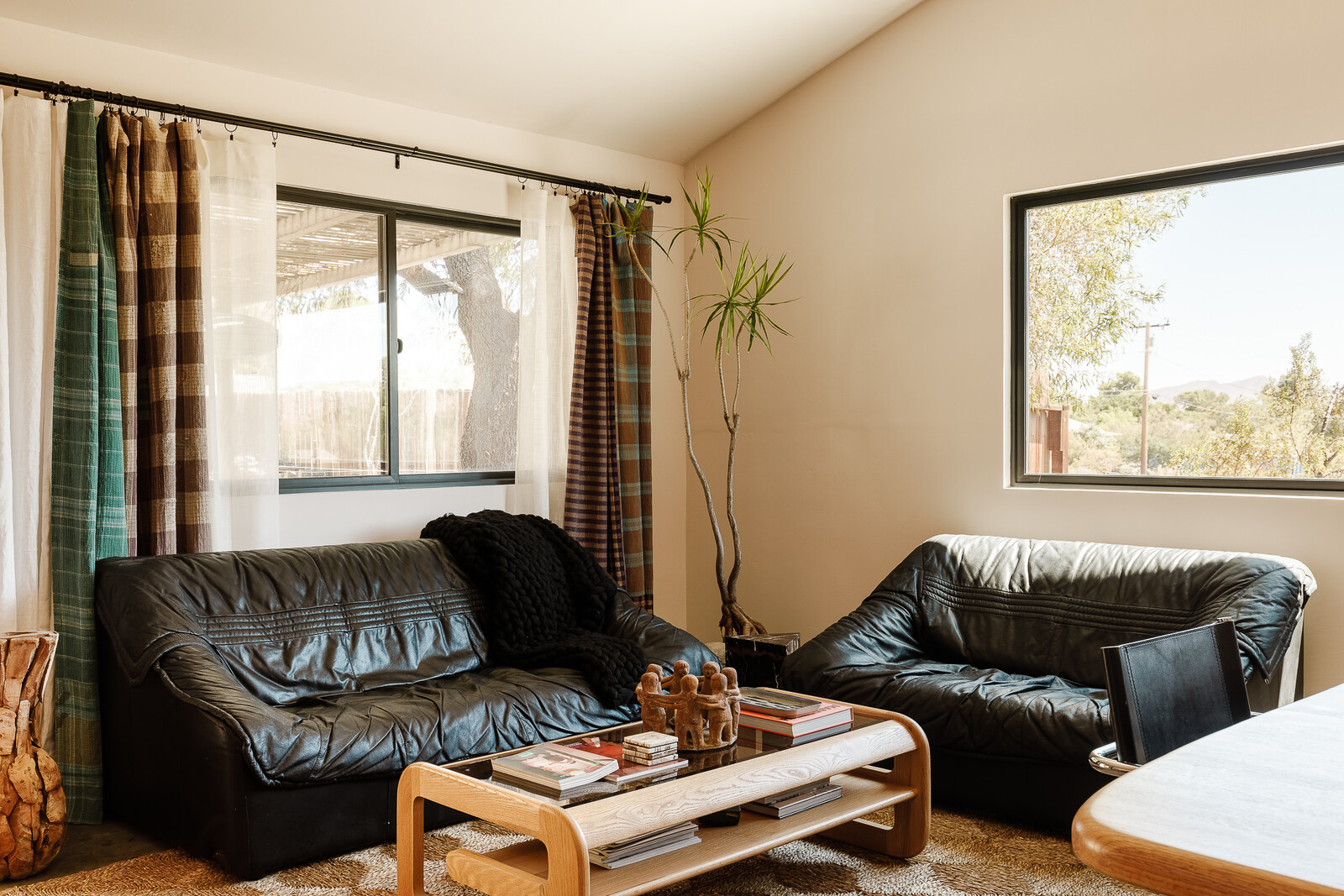 The black leather sofa and loveseat are vintage Italian, and the coffee table is vintage Lou Hodges. Both are from Vintage on Point. The draperies are from Etsy.