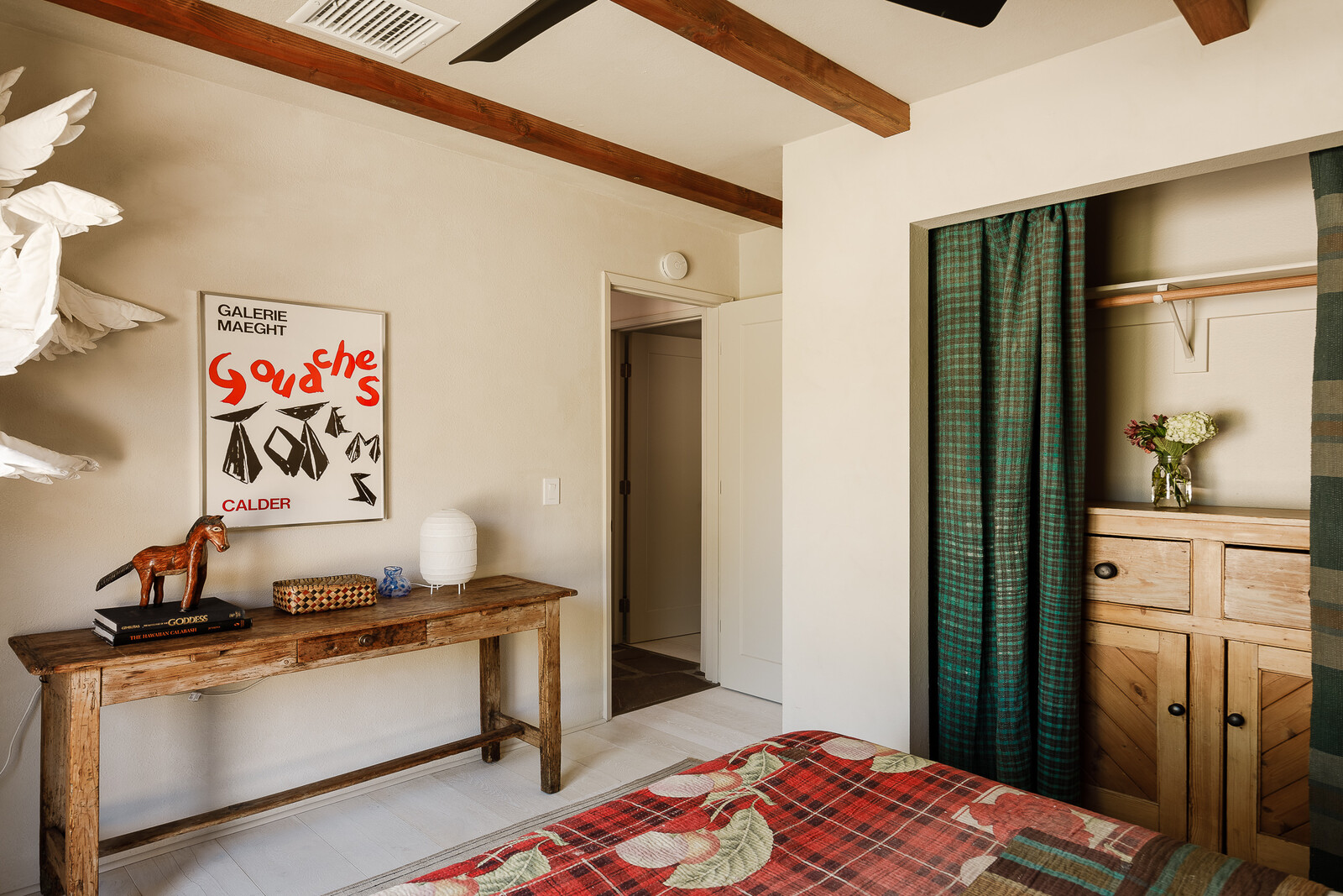 In the guest room, a vintage French country wooden hutch in the closet and a vintage rustic wooden table were both sourced from the Rose Bowl Flea. The closet drapes are from Etsy.