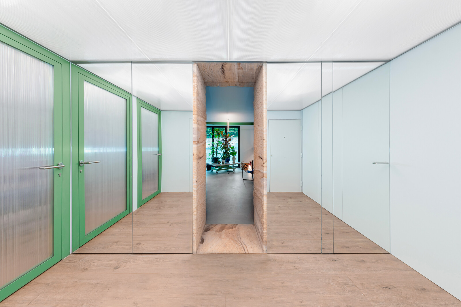 Polycarbonate ceilings frame the entry area and the bedroom doors, allowing light to penetrate the spaces and bounce off the mirrored doors hiding storage areas.