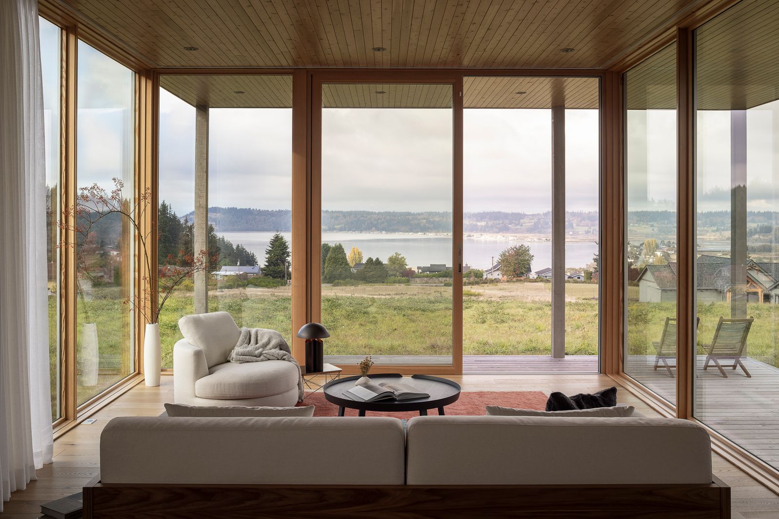 The living area is encased on three sides by window walls, which slide open to the deck and offer views of the meadow and water beyond. "I love sitting in the living room and staring out to the water, the doors just melt away and it feels very quiet,