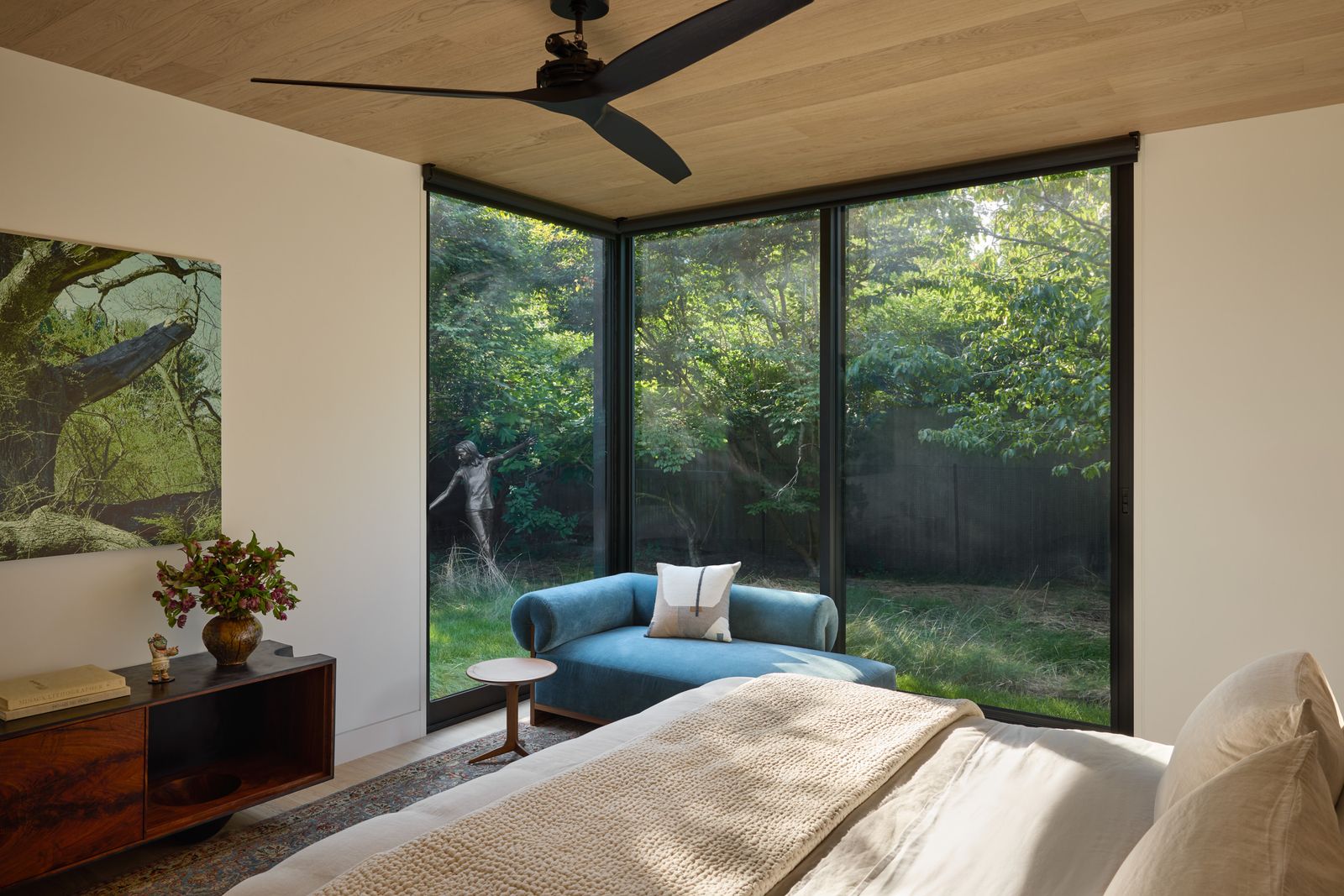 In the primary suite, a lounge chair from Moving Mountains sits in the corner window. The wall-hanging photograph is by James Welling.