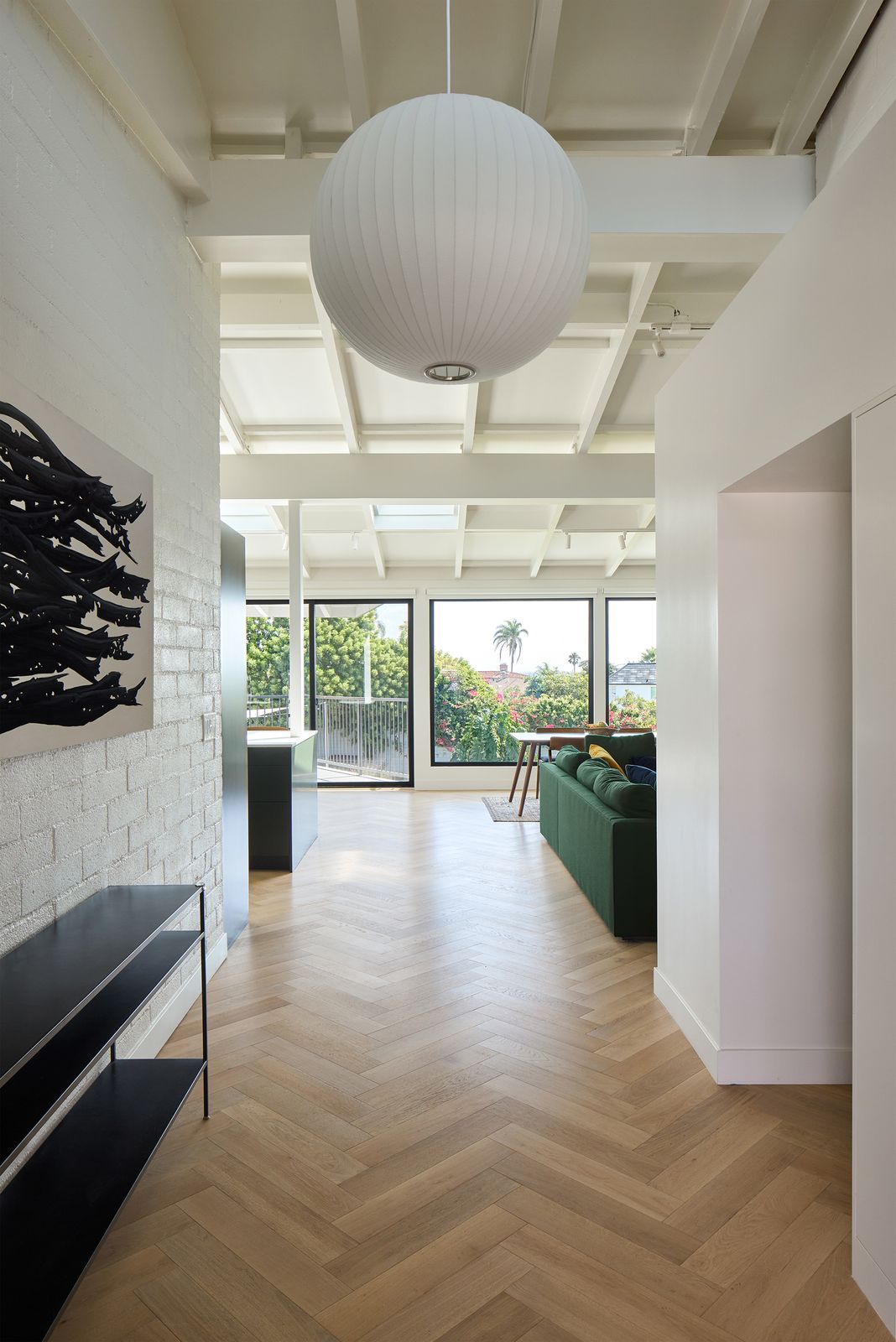 Portions of the home's original masonry walls were revealed and given a fresh coat of paint. New white oak floors help brighten up the space, while the herringbone pattern adds personality.