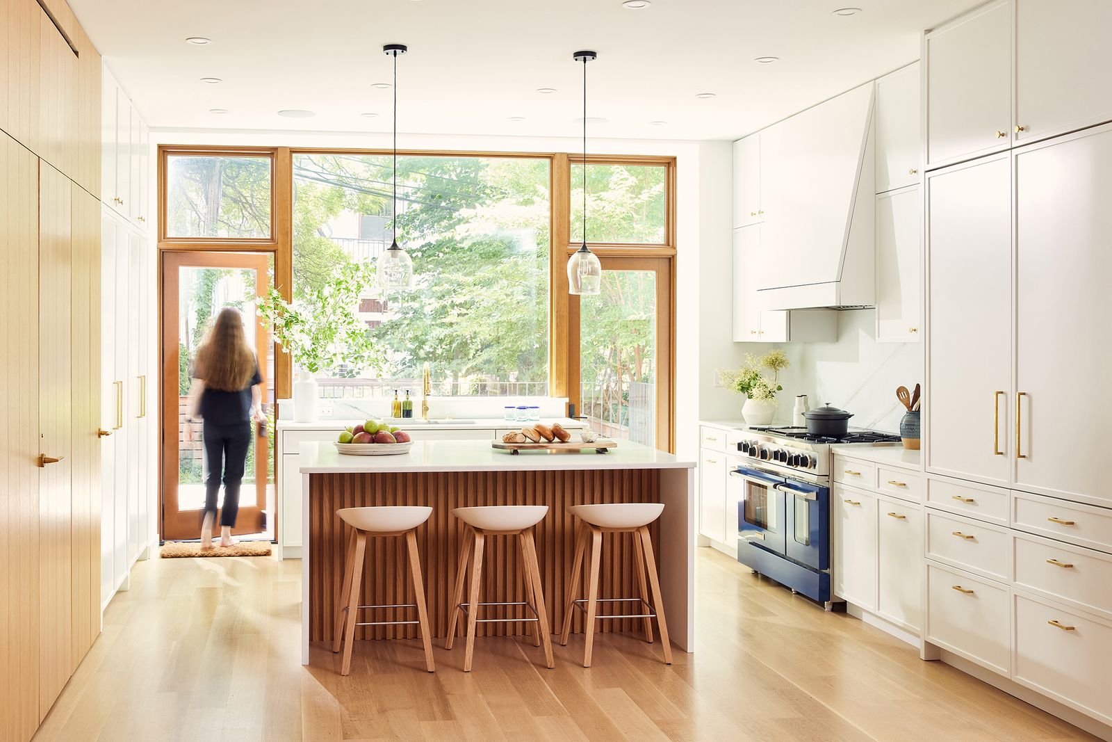 New engineered oak floors and oak cabinetry lend a warmth to the interiors, especially the new open living area containing the kitchen, dining, and living area on the main floor. The glass pendants over the island were made by the father of one of the owners, who owns Pablo Glass in Woodstock, New York.