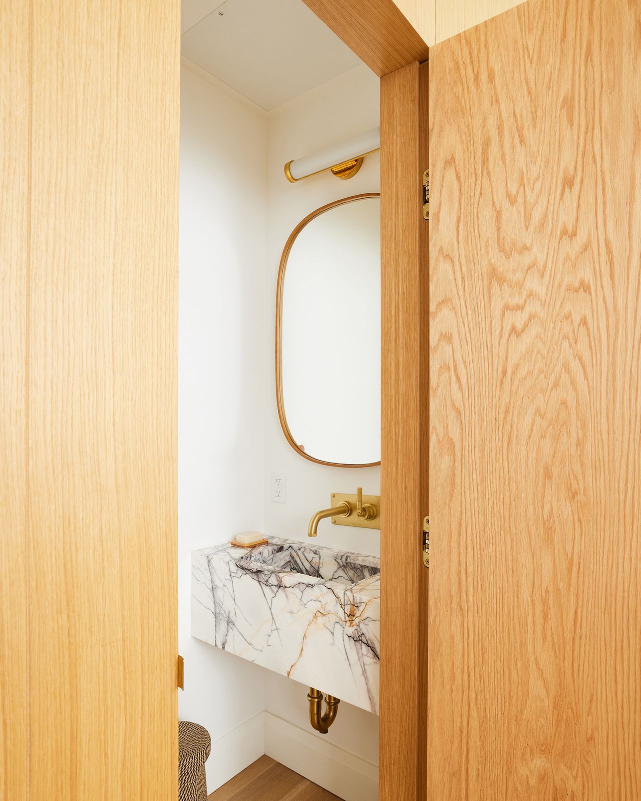 The powder room contains a custom stone sink in lilac marble sourced from ABC stone. The purple veining nods to the original bold purple of the front door.