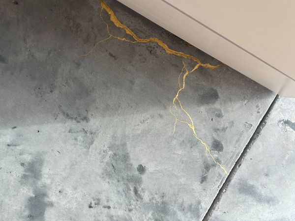 In many of the home's corners, cracks appeared in the new concrete flooring once it was poured, including in this spot in the living room. Tajima and Bradley filled the cracks with grout and then gilded each of those grout lines to give the look and feel of kintsugi.