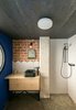 Modern home with Bath Room, Ceiling Lighting, Open Shower, Concrete Floor, Ceramic Tile Wall, and Wood Counter. The bathroom is the only fully enclosed room in the apartment, and it sits below the new mezzanine level. Geometric tiles have been used to create a playful backsplash against the raw brick wall behind the sink. Photo 10 of #UPHouse