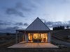 Modern home with Exterior, House Building Type, Shed Building Type, Barn Building Type, Cabin Building Type, Small Home Building Type, Farmhouse Building Type, Metal Roof Material, Prefab Building Type, Gable RoofLine, Beach House Building Type, Wood Siding Material, and Shed RoofLine. The simple form of this humble family home bravely holds its own on the hilltop, a warm glowing light welcoming you home. Photo 9 of Karangahake House