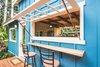 Modern home with Dining Room, Light Hardwood Floor, Ceiling Lighting, Accent Lighting, Track Lighting, Bar, Stools, and Medium Hardwood Floor. An outdoor deck and bar area with a mango wood counter and a massive window create an indoor/outdoor living experience. Photo 2 of Paradise Tiny Home
