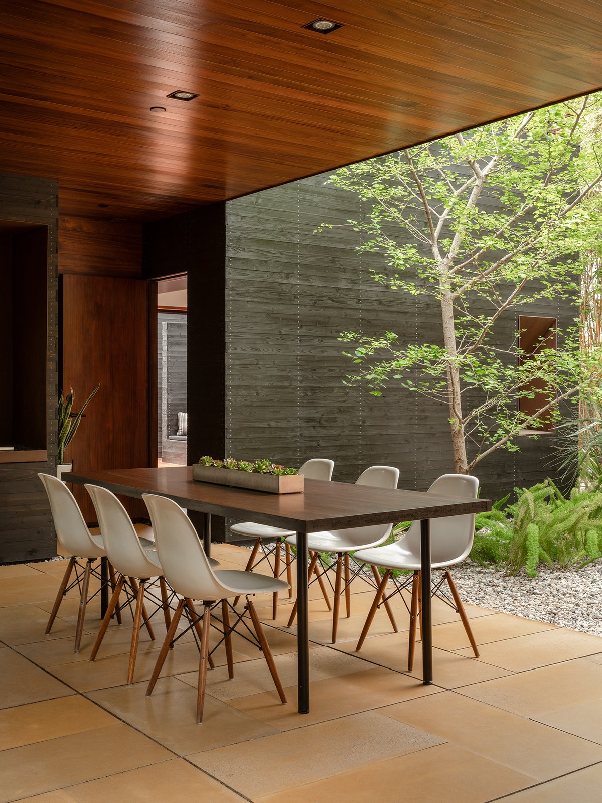 Modern home with Dining Room, Chair, Recessed Lighting, and Table. A covered dining area marks the end of the communal areas, with a door leading to the master bedroom. Photo 12 of Venice House by Sebastian Mariscal