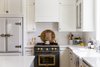 Modern home with Kitchen, Wall Oven, Refrigerator, and White Cabinet. The elegant pairing of Big Chill's Classic Fridge in White with Satin Nickel trim and Big Chill's 36" Classic Stove in Custom Basalt Gray with Brushed Brass trim coordinates harmoniously in Kirsten Krason's kitchen. Photo 11 of Stunning Kitchen Renovation by House of Jade