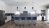 Modern home with Kitchen, Quartzite Counter, Light Hardwood Floor, Refrigerator, Range, Ceiling Lighting, Pendant Lighting, Microwave, Wood Cabinet, White Cabinet, Mosaic Tile Backsplashe, Wine Cooler, Dishwasher, Drop In Sink, and Recessed Lighting. Kitchen Photo of The Southold House