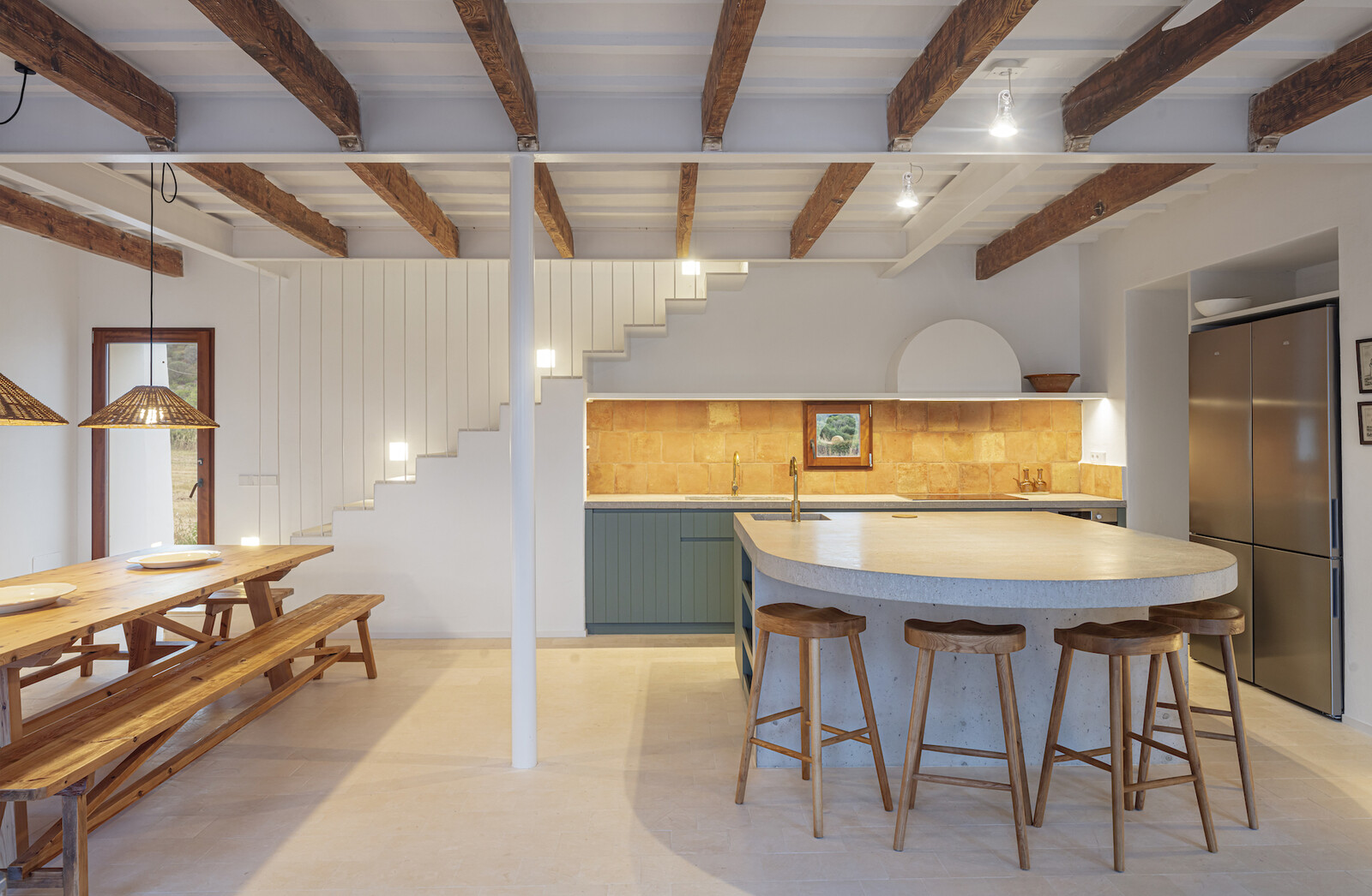 A custom-built island anchors the kitchen-dining area, the most social area of the home. The dining table and chairs were made with wood rescued during the renovation process.